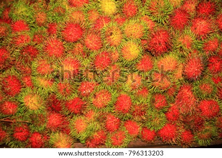 background of ripe exotic fruit Rambutan, which are laid out on the counter on a tropical the market and fill the entire surface of the shop window counter