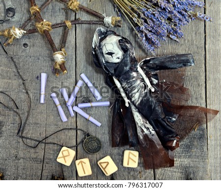 Scary doll in black witch dress, runes, lavender and pentagram on planks. Occult, esoteric, divination and wicca concept. Halloween vintage background