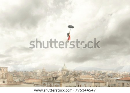 Surreal moment of a woman flying with her umbrella over the city Royalty-Free Stock Photo #796344547
