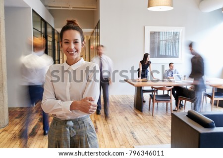 Portrait of young white woman in a busy modern workplace Royalty-Free Stock Photo #796346011