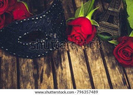 red fresh roses with masque and eiffel tower on wooden table, retro toned