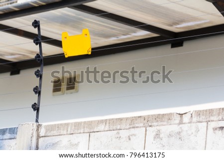 high voltage security electric fence on concrete wall oh house, blank yellow sign hang on electric fence