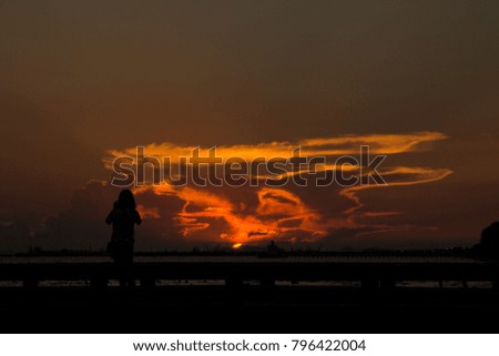 silhouette asian girl take the photo from mobile phone at sunset in the Mae Rumphueng Beach in  Rayong, Thailand