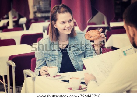 young couple of tourists examining a map and having breakfast in a cafe