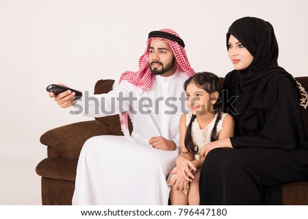 Arab family watching TV at home and using remote control with white background