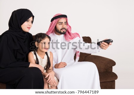 Arab family watching TV at home and using remote control with white background