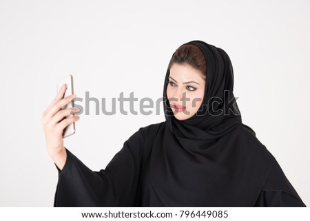 beautiful arab girl taking selfie with her smart phone on white background