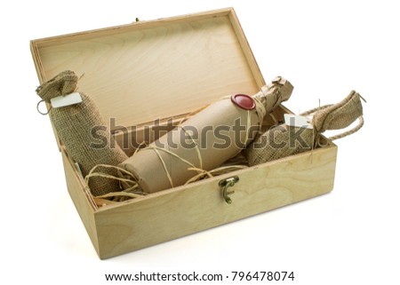 A bottle of  exclusive wine wrapped in the paper and sealed with the blank wax seal in the wooden box with sacks of seasonings isolated on the white background. Available space for a logo or text