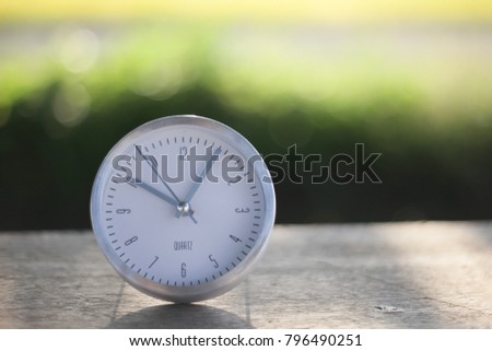 silver rounded clock on bokeh background. selective focus and shallow D.O.F