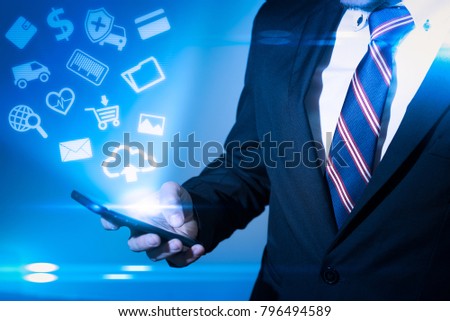 the abstract image of the businessman looking to the application icon hologram on his smartphone. the concept of communication, software, application, internet of things and future life.