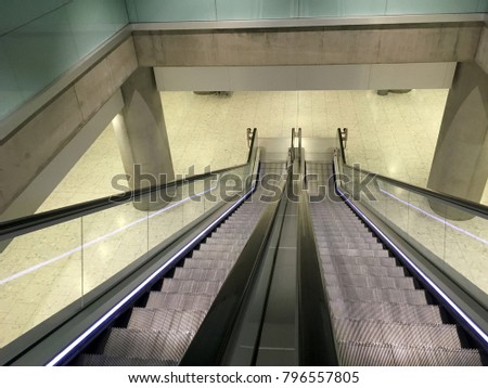 Looking down at an Escalator with no people. Escalator going down to another floor in a metro station. Clean and sleek modern interior design at a transportation hub. Clean interior design. 