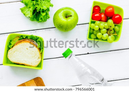 homemade lunch with apple, grape and sandwich in green lunchbox 