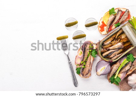 Vodka and a set of sandwiches with sprats, and caviar, onion and parsley, on a wooden background. Top view. Copy space.