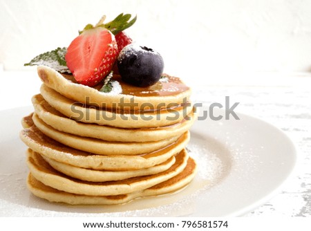 American pancakes with berries on a light background.
