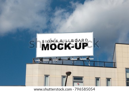 The mock up of the large billboard over the building with clipping path, blank white space and metal frame for advertisement outdoors on top of the building with spotlight