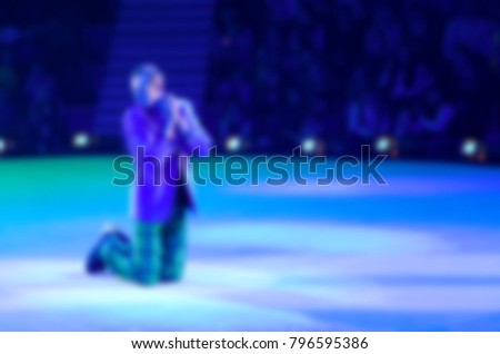 Abstract blurred image of tour of circus on ice. Performance of sad clown, without focus, background   