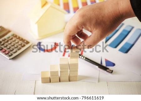 Hand of business aranging wood block stacking as step stair graphs and financial data on background. Business for growth success process concept.