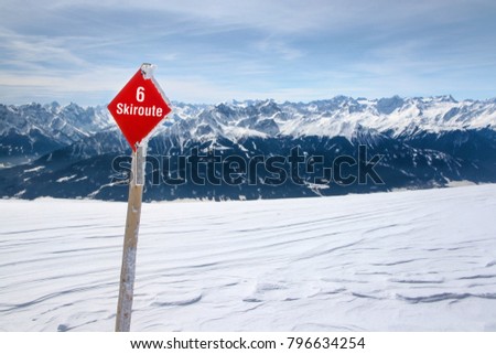 Red ski route 6 sign on fresh snow with Austrian Alps and sky in background photographed in Nordpark, Innsbruck