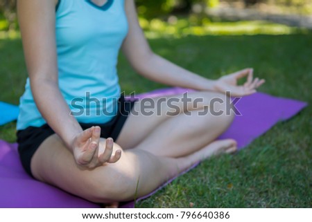 Young woman practices yoga and meditates in the lotus pose at park,Selective Focus