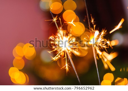 Bengal fire, abstract blur sparklers and colorful bokeh, new year tree background.