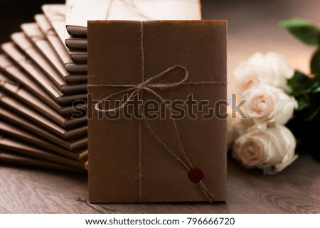 
Gift photo frame beautifully packaged in craft paper lies on a wooden floor with a white rose