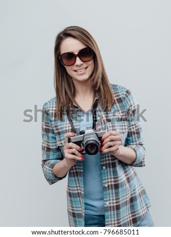 Smiling female photographer and tourist, she is posing and holding a digital camera