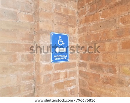 blue accessible entrance sign on red brick wall