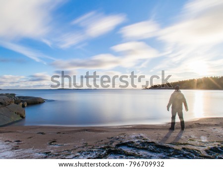 Traveller searching for new horizons on an empty beach, long exposure