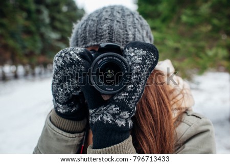 Young photographer takes pictures of winter forest with a camera