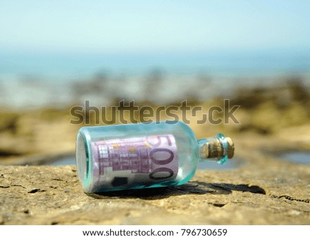Five hundred (500) euro banknote inside a bottle over the rocks on a beach in southern Europe