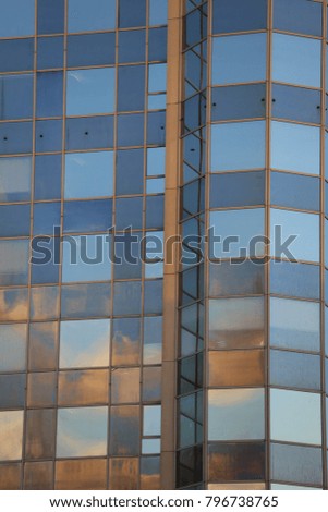Close up view of a modern building made of many brillant glasses and windows. Pattern with lines and rectangles. Blue color and lights. Architectural design of an urban building located in France. 