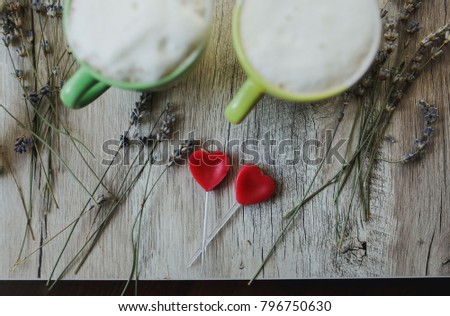 Two cups of cappuccino with small candy hearts on the background. Lavender on the wooden tray background. Green and yellow cups. Perfect instagram layout. Rustic food photo. Happy Valentine's day idea