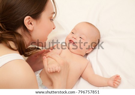 Picture of happy mother with adorable baby smiling and lying on bed
