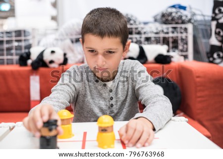 Young boy playing with black and yellow figures in the shop, waiting for parents to finish shopping 