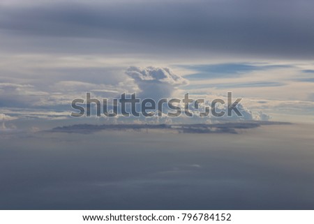 View of white big clouds of different forms in the blue sky. The picture has been taken from an airplane. Strange shapes of cumulus in the space. Natural aerial image. Beautiful unusual cloudscape. 