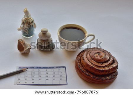 early booking dreams and plans: a cup of coffee, a bun with poppy,  calendar sheet, pencil,a souvenir from the seaside resort of the bottle with blue sand and seashell on gray background