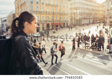 Young traveler woman admiring beautiful sunny Praca de Luis Camoes square in Lisbon, Portugal.Sunny day in Lisbon, perfect place for traveling in Europe.Crowded Lisbon streets.Backpacker photographer 