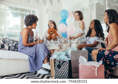 Pregnant woman celebrating baby shower party with friends. Pregnant woman receiving gifts from friends. Royalty-Free Stock Photo #796828333