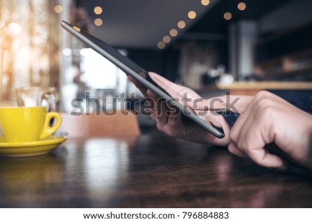 Closeup image of a hand pointing , touching and using tablet pc with blur background in cafe
