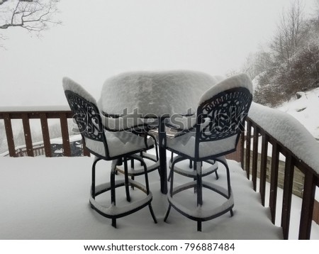 Snow Storm View of Café Table and Chairs During a Blizzard; Snow on Table Resembles a Large Piece of Angel Food Cake and the Funny  Incongruity of Classy Summer Furniture in a Blizzard of Snow