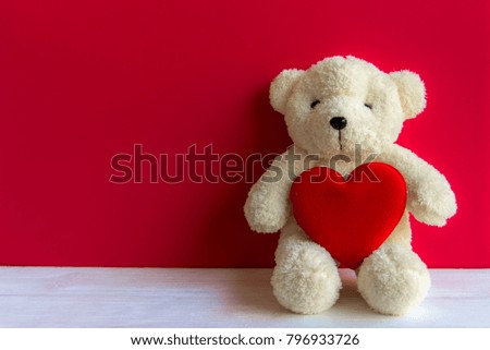 Cute teddy bear with red heart on old wood, copy space, red background. Valentine Concept
