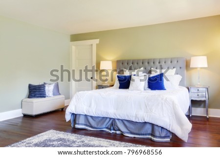 Luxurious master bedroom with green walls and  white and blue bed accented with grey tufted headboard. Northwest, USA