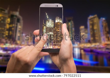 Hand with smartphone taken pictures of Dubai Marina skyline, UAE
