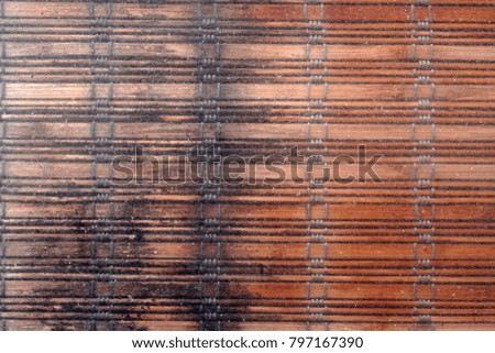 Textured background of woven bamboo window shades seen through a shabby PVC foil over them. Background, close up