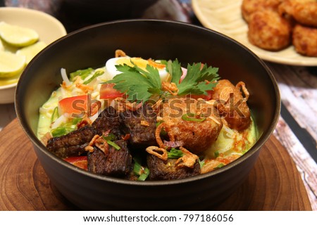 Soto Medan. Creamy coconut milk soup with fried beef cubes, glass noodles, bean sprouts, egg, and potato cake from Medan, North Sumatra. Royalty-Free Stock Photo #797186056