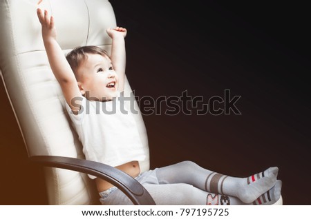 Child in a chair, in a white t-shirt is very happy about the win or the goal, place for inscription