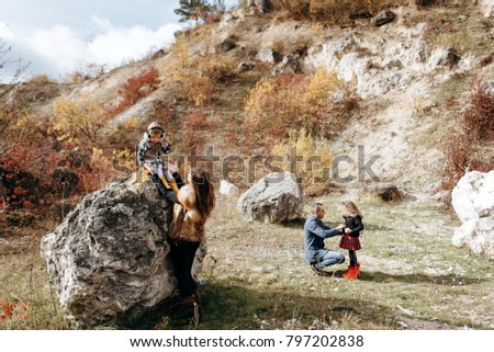 beautiful young family in the mountains in autumn. walk near the stones and yellow trees. family happiness. two daughters and parents