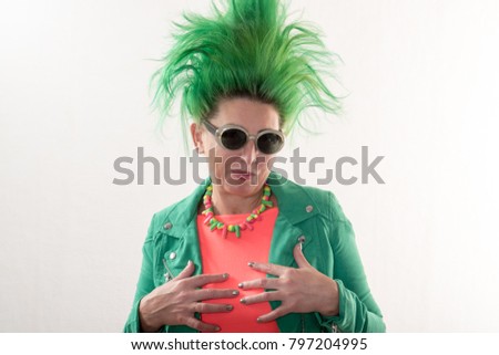 A caucasian girl in a green dress and with green hair is preparing for the holidays. Suit of the teacher of primary classes. The concept of happy holidays and good mood.
