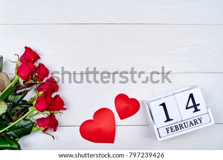 Valentines Day background with bouquet of red roses, two hearts and february 14 wooden block calendar, copy space. Greeting card mockup. Love concept. Top view, flat lay