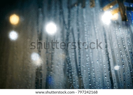Multicolor light from LED lights and a droplets of raining close up and bokeh. Image has grain or blurry or noise and soft focus when view at full resolution. (Shallow DOF, slightly motion blur)